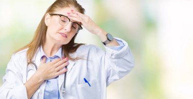 Orta yaş olgun doktor kadın üzerinde tıbbi bir palto giyiyor izole arka plan hastalık ve ateş, grip ve soğuk, virüs hasta için alın dokunmadan