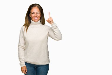 Ve kendinden emin ve mutlu gülümseyerek süre parmak numaralı yukarıyı gösteren izole arka plan üzerinde kış kazak giyen güzel orta yaş yetişkin kadın.