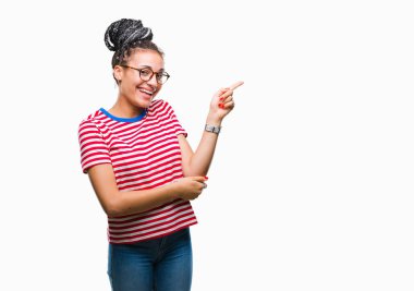 Kameraya bakarak yan el ve parmak ile işaret yüzünde kocaman bir gülümseme ile izole arka plan üzerinde gözlük takan saç Afro-Amerikan kız Genç örgülü.