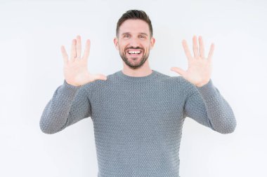 Gösterilen ve parmakları ile işaret izole arka plan üzerinde rahat kazak giyen genç yakışıklı adam kendinden emin ve mutlu gülümseyerek süre on numara.