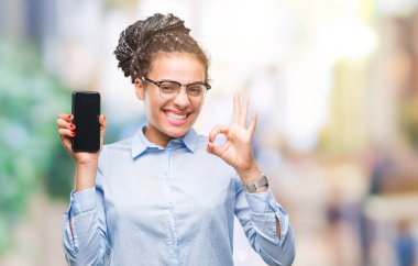 Genç örgülü saç Afro-Amerikan iş kız gösteren ekran akıllı telefon parmak, mükemmel sembolü ile ok işareti yapıyor izole arka plan üzerinde