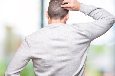 İzole arka plan geriye düşünme hakkında şüphe kafasına el ile üzerinden sweatshirt giyen genç yakışıklı adam