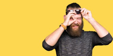 Genç hipster adam giyen güneş gözlüğü el gülümseyen, ok jest yapıyor göz parmakları ile mutlu yüz üzerinden seyir.