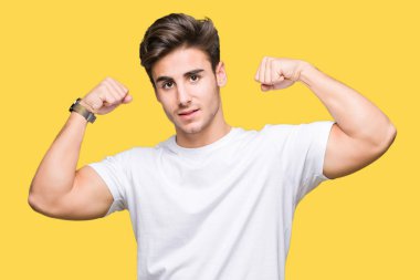 Kol kasları gururlu gülümseyen gösterilen izole arka plan üzerinde beyaz t-shirt giyen genç yakışıklı adam. Fitness kavramı.