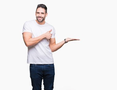 Yakışıklı adam beyaz üzerinde beyaz t-shirt giyen arka plan gösteren palm el izole ve mutlu ve neşeli gülümseyen thumbs up, ok hareketi ile yapıyor