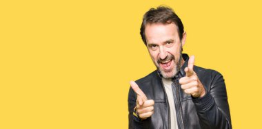 Fotoğraf makinesi ile mutlu ve komik yüz için işaret parmakları ceket siyah deri giyen orta yaş yakışıklı adam. İyi enerji ve vibes.