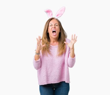 Paskalya tavşan kulakları üzerinde giyen orta yaş esmer kadın deli ve deli bağırarak ve agresif ifade ve silah kaldırdı bağırmaya arka izole. Hayal kırıklığı kavramı.