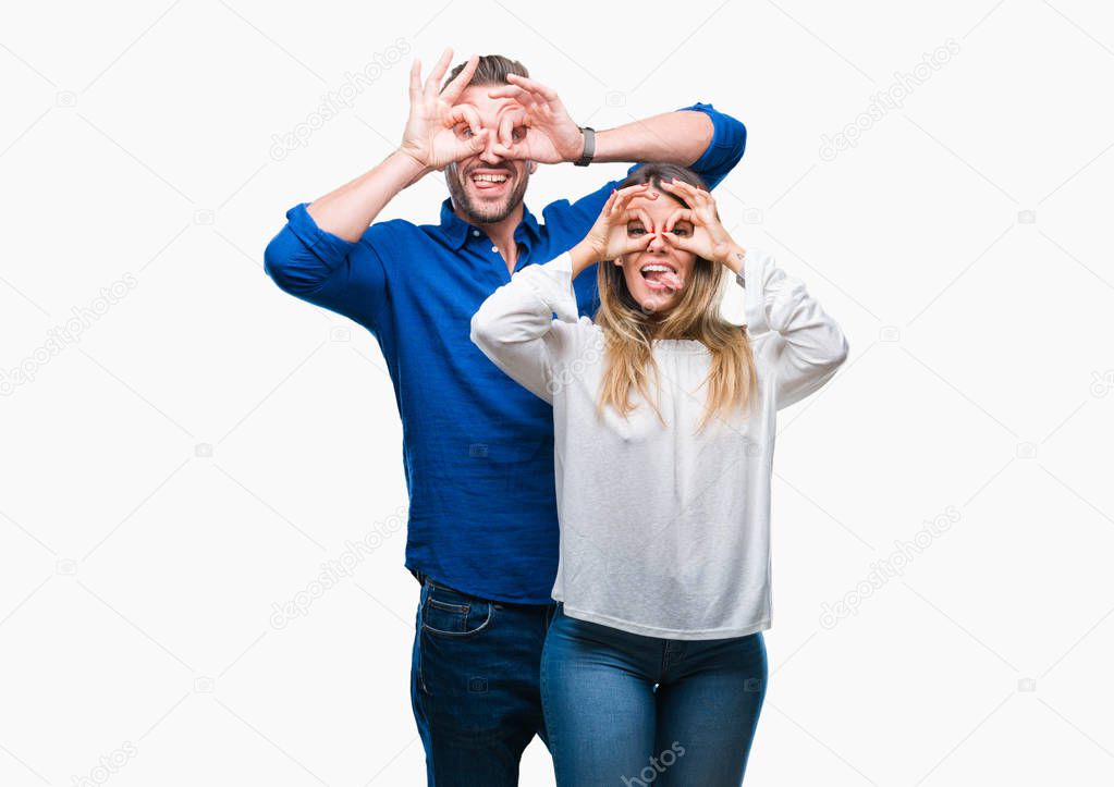 Young couple in love over isolated background doing ok gesture like binoculars sticking tongue out, eyes looking through fingers. Crazy expression.