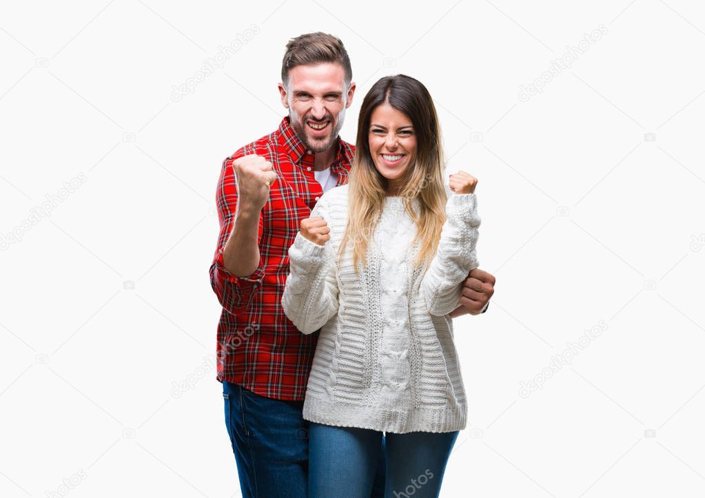 Young couple in love wearing winter sweater over isolated background very happy and excited doing winner gesture with arms raised, smiling and screaming for success. Celebration concept.