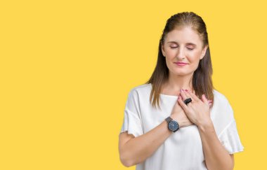 Orta yaş olgun güzel kadın ile gülümseyen izole arka plan yüzünden kapalı gözler ve yüzünde minnettar jest ile göğüs üzerinde eller. Sağlık kavramı.