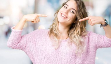 Güzel sarışın genç kadın kendine güvenen gösterilen ve işaret parmakları diş ve ağız ile gülümseyen izole arka plan üzerinde. Sağlık kavramı.