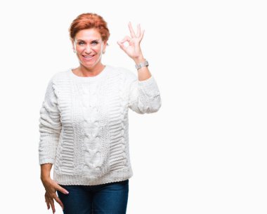 İzole arka plan el ve parmaklar ok işaretiyle yapıyor olumlu gülümseyen üzerinde kış kazak giyen Atrractive üst düzey beyaz Kızıl saçlı kadın. Başarılı ifade.