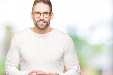 Arka plan eller üzerinde gözlük takan genç yakışıklı adam birlikte izole ve rahat ve neşeli gülümseyen parmak çarpı işareti. Başarı ve iyimser