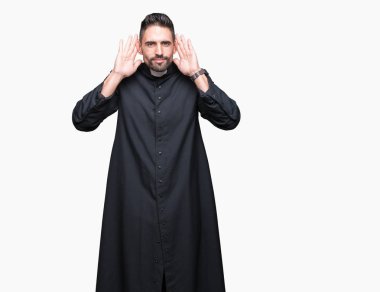 Genç Hıristiyan rahip kulak jest, dedikodu için meraklı her iki ellerde dinliyoruz izole arka plan üzerinde. İşitme sorunu, sağır