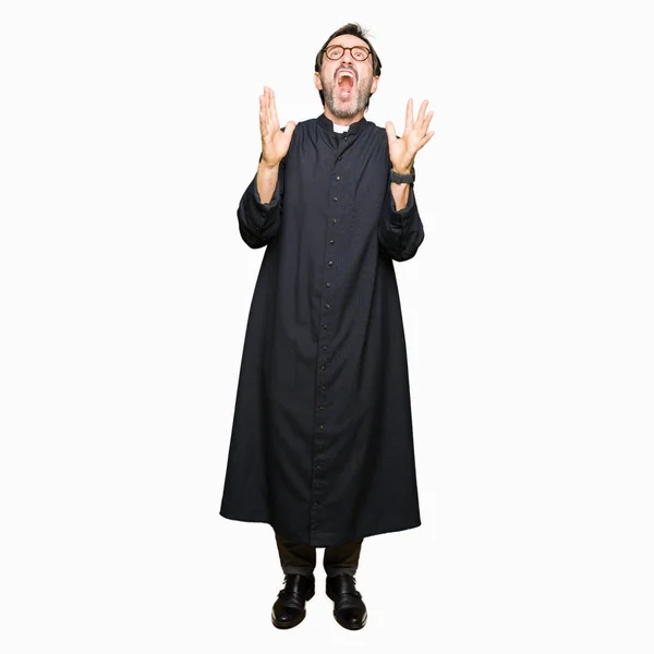 中年牧师男子穿着天主教长袍疯狂和疯狂的大喊大叫 积极的表情和手臂抬起来 挫折的概念 — 图库照片