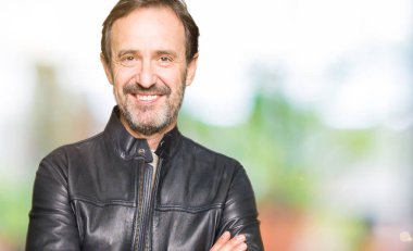 Siyah deri ceket mutlu yüz çapraz silah kameraya bakarak ile gülümseyen giyen orta yaş yakışıklı adam. Olumlu bir kişi.