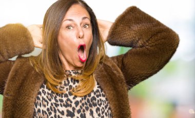 Güzel orta yaş zarif kadın giyiyor vizon deli ceket ve baş, korkuyor ve açık ağzı ile şok sürpriz elleriyle korkuttu