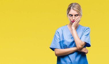 Genç güzel sarışın doktor cerrah hemşire kadın izole arka plan düşünme seyir üzerinde yorgun ve sıkılmış çapraz silah depresyon sorunları ile.