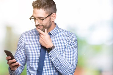 Genç iş adamı izole arka plan ciddi bir yüz düşünme hakkında soru, çok karışık bir fikir üzerinde akıllı telefon kullanma