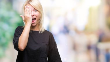 El yüz ve sürpriz duygu kendinden emin gülümseme ile tek gözüyle kapsayan izole arka plan genç güzel sarışın kadın.