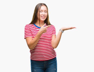 Hayret ve el ile sunulması ve parmak ile işaret ederken kameraya gülümseyen izole arka plan üzerinde beyaz genç güzel kadın.