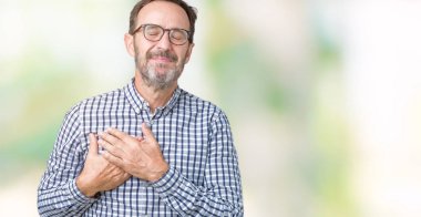 Göğüs kapalı gözlerle ellerinde ve yüzünde minnettar jest ile gülümseyen izole arka plan üzerinde gözlük takan yakışıklı orta yaş zarif üst düzey iş adamı. Sağlık kavramı.