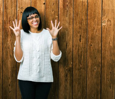 Güzel genç Afro-Amerikan kadın gözlük gösterilen ve parmakları ile işaret izole arka plan üzerinde dokuz kendinden emin ve mutlu gülümseyerek iken numara.