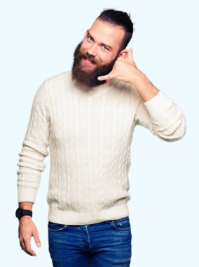 Gülümseyen kış kazak giyen genç hipster adam el ve parmak telefonda konuşmak ile telefon jest yapıyor. Kavramları iletişim.