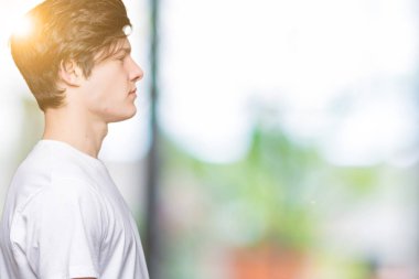 İzole arka tarafına, seyir üzerinde rahat beyaz t-shirt giyen genç yakışıklı adam sakin ol kendine güvenen gülümseme ile doğal yüz pozuyla profili.