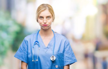 Genç güzel sarışın doktor cerrah hemşire kadın komik surat ile yanakları şişirme izole arka plan yüzünden. Ağız ile hava, deli ifade şişirilmiş.