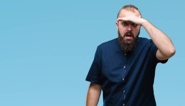 Genç beyaz hipster adam izole arka plan çok mutlu ve gülümseyen uzakta el ile üzerine kafa arıyorum. Arama kavramı.