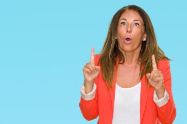 Güzel orta yaş iş yetişkin kadın izole arka plan üzerinden hayran ve yukarıya bakıp parmakları ile işaret şaşırttı ve silah kaldırdı.