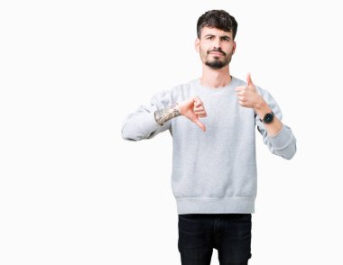 Genç yakışıklı adam kazak giyiyor izole arka plan yapmaya başparmak üzerinde yukarı ve aşağı, anlaşmazlık ve anlaşma ifade. Deli çatışma