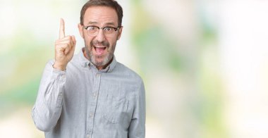 Başarılı fikirle izole arka plan işaret parmağı üzerinde gözlük takan yakışıklı orta yaş zarif komuta sizde. Çıktıktan ve mutlu. Bir numara.