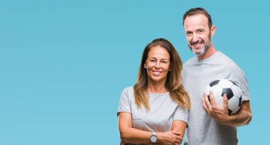 Futbol futbol topu bir gülen surat konumu olan izole arka plan üzerinde tutarak ve diş gösterilen kendine güvenen bir gülümsemeyle gülümseyerek orta yaş İspanyol çift