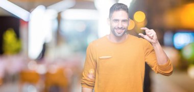 Yakışıklı genç gülümseyen izole arka plan ve süre seyir ve kamera boyutu işaret parmaklarıyla yapıyor el ile kendinden emin eller üzerinde. Ölçü kavramı.