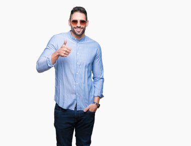 Genç yakışıklı adam hareketi el ile mutlu yaşasın yapıyor izole arka plan üzerinde güneş gözlüğü takıyor. Kameraya bakarak başarı gösteren ile ifade onaylama.