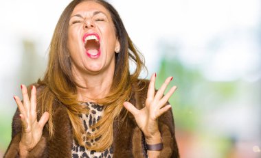 Güzel orta yaş zarif kadın vizon ceket deli ve deli çığlık giyiyor ve agresif ifade ve silah ile bağırdı kaldırdı. Hayal kırıklığı kavramı.