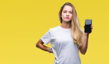 Genç güzel sarışın kadın gösteren ekran smartphone akıllı yüzünde ciddi düşünme emin bir ifade ile izole arka plan üzerinde