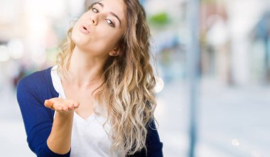 Güzel sarışın genç kadın bir öpücük el ile güzel ve seksi olmak hava üfleme kamera bakarak izole arka plan üzerinde. Aşk ifade.