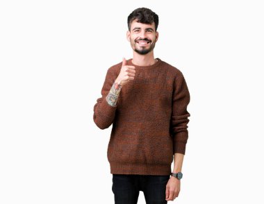 Hareketi el ile mutlu yaşasın yapıyor izole arka plan üzerinde kış kazak giyen genç yakışıklı adam. Başarı gösteren kameraya bakarak ifade onaylama.