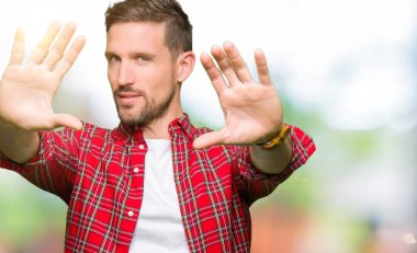 Yakışıklı adam giyiyor rahat gömlek çerçeve kullanarak yapıyor gülen eller avuç içi ve parmaklar, kamera perspektif