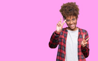 Gözlük kamera zafer işareti yapıyor parmak gösteren seyir gülümseyen izole arka plan üzerinde güzel genç Afro-Amerikan kadın. İki numaralı.