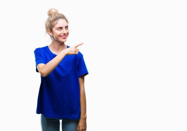 İzole arka neşeli bir gülümseme ile el ve parmak kadar kameraya bakarak yüzündeki mutlu ve doğal ifade ile yan ile işaret yüz üzerinde mavi t-shirt giyen genç güzel sarışın ve mavi gözlü kadın.