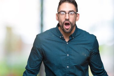 Arka plan korkuyor ve şok sürpriz ifade, korku ve heyecan yüz üzerinden gözlüklü genç yakışıklı iş adamı izole.