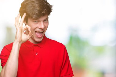 İzole arka plan el ve parmaklar ok işaretiyle yapıyor olumlu gülümseyen üzerinde kırmızı t-shirt giyen genç yakışıklı adam. Başarılı ifade.