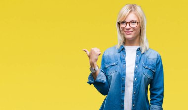 Seyir ve başparmak yanında yukarıyı mutlu yüz ile gülümseyen izole arka plan üzerinde gözlük takan genç güzel sarışın kadın.