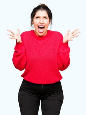 Kırmızı kazaklı ve topuz ile silah kaldırdı deli ve başarı için hayran kutluyor ve açık gözleri heyecanlı çığlık giyen genç güzel kadın. Kazanan kavramı