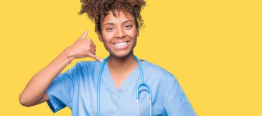 Genç Afro-Amerikan doktor kadın yapıyor gülümseyen izole arka plan üzerinde telefon hareketi ile el ve parmak telefonda konuşuyor gibi. Kavramları iletişim.