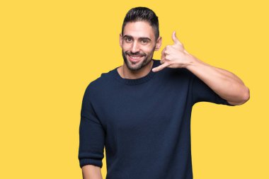 Kazak yapıyorsun gülümseyen izole arka plan üzerinde giyen genç yakışıklı adam telefon hareketi ile el ve parmak telefonda konuşuyor gibi. Kavramları iletişim.